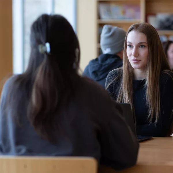 students sitting at tables in a classroom engaged in group discussions